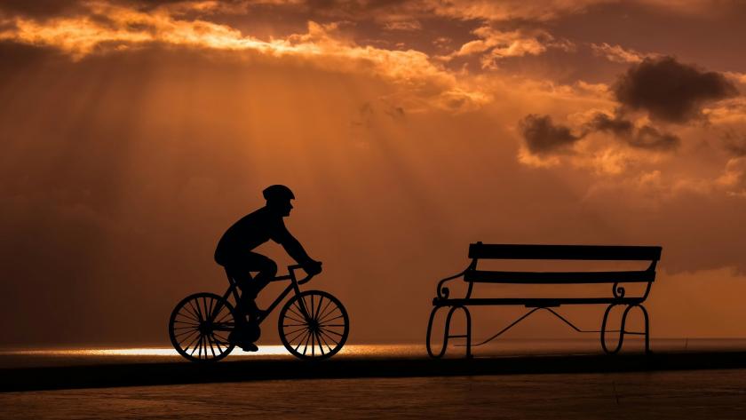 ciclista llegando a un banco al atardecer ciclista llegando a un banco al atardecer