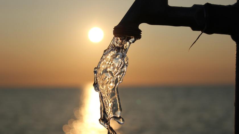 agua agua saliendo de un grifo con el atardecer de fondo