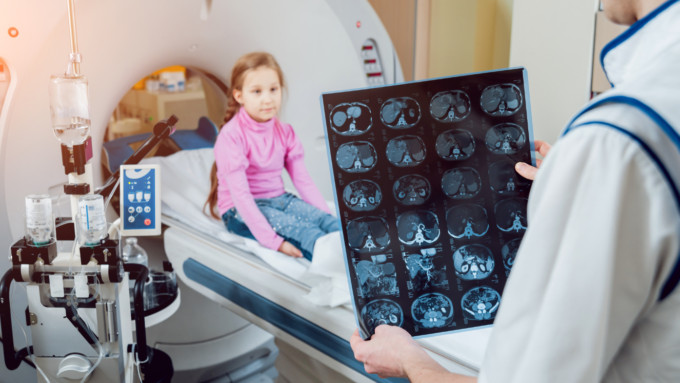 niña en camilla sentada frente a médico que mira radiografía