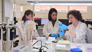 tres mujeres con bata blanca de frente en laboratorio de cáncer genitourinario