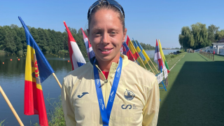 Mujer joven posando con una medalla en unos juegos deportivos con las banderas de los países participantes a la izquierda