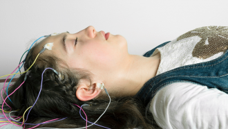 parte superior del cuerpo de una joven tumbada y dormida con cables y sensores colocados en la cabeza