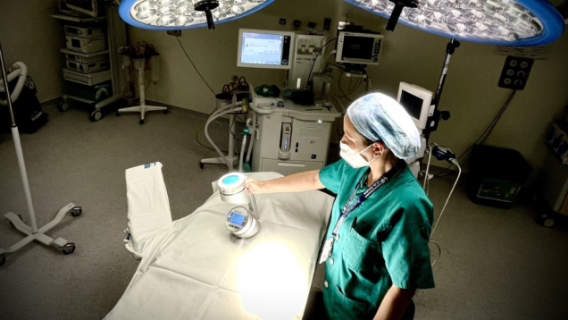 profesional sanitaria en quirófano con un aparatito sobre mesa de quirófano