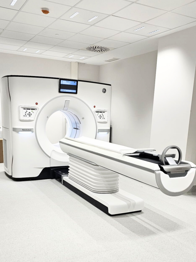 Máquina blanca con un soporte donde se tumba el paciente y que entra por un aro donde se le hace una tomografía