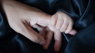 mano de adulto y mano de bebé agarrando un dedo