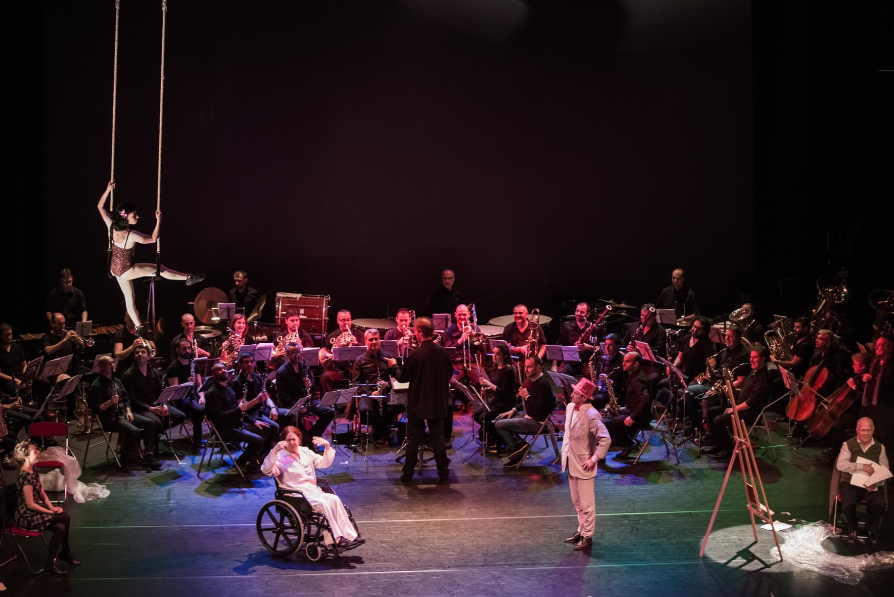 Orquesta sobre un escenario acompañada de varios personajes