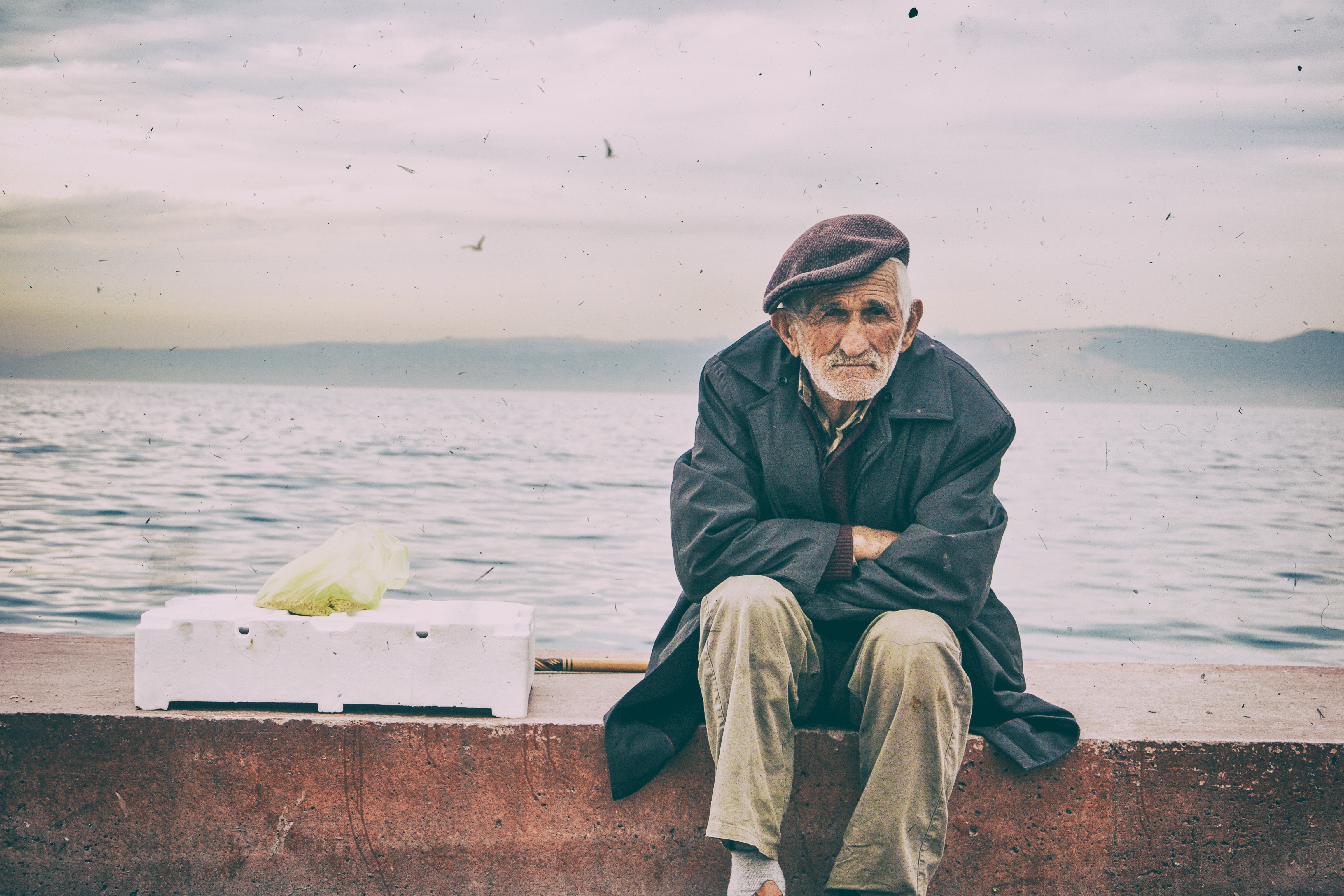 Anciano sentado de espaldas al mar
