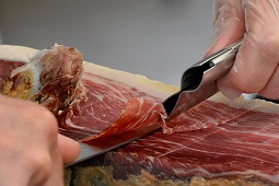 primer plano de un jamón siendo cortado a cuchillo
