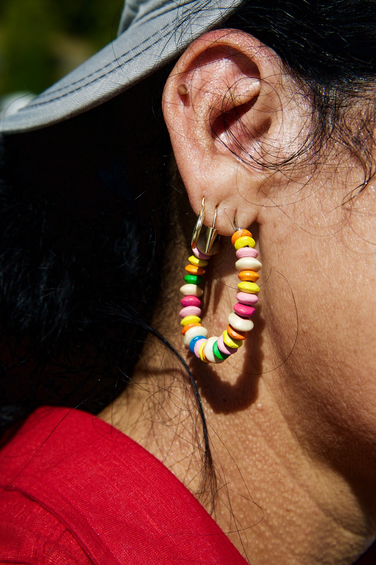 foto de oreja con pendiente de colores y piercings 