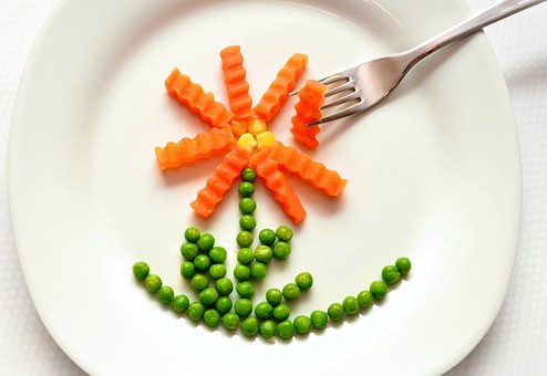 dibujo de una flor en un plato hecho con zanahoria y guisantes