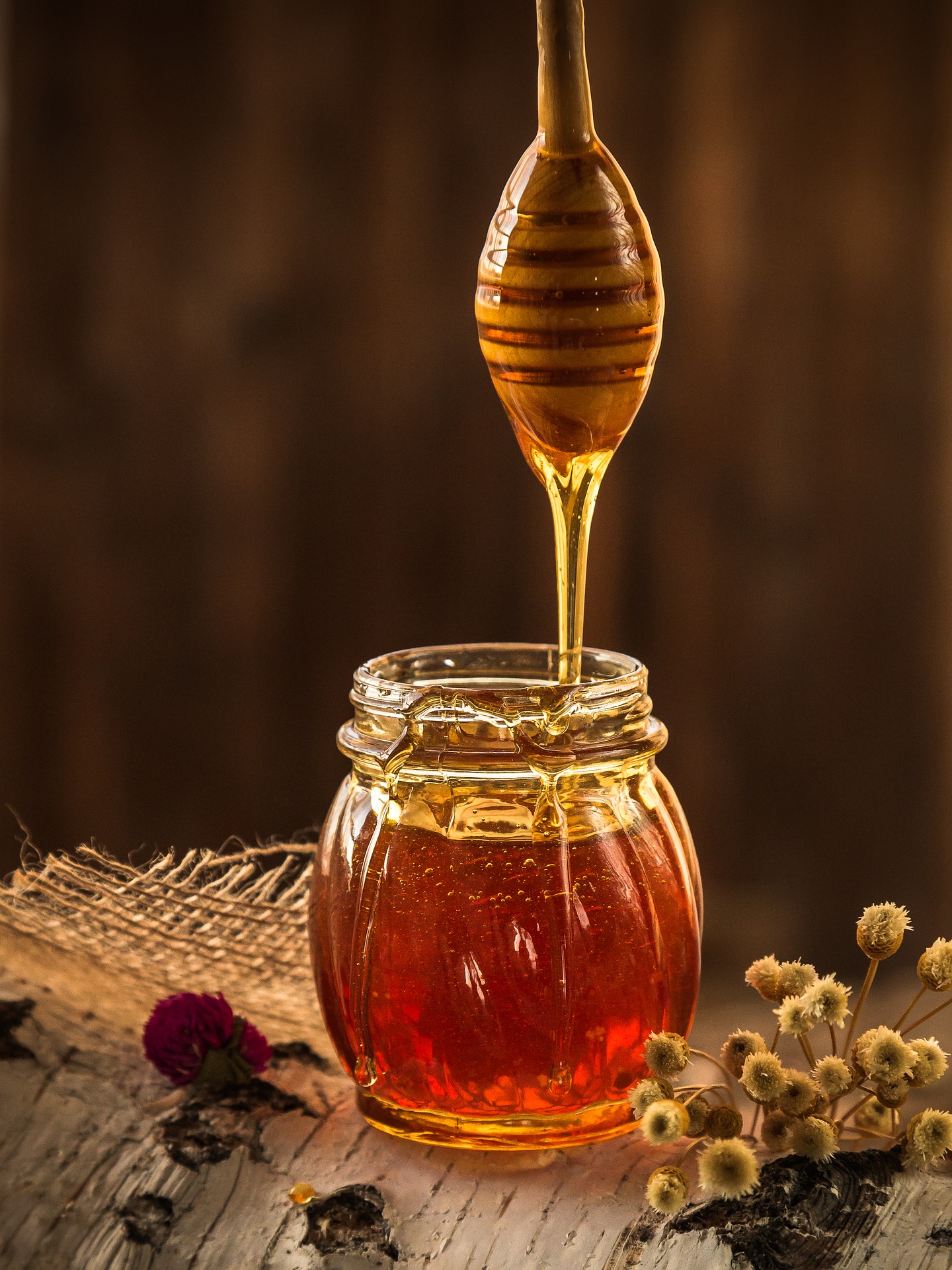 palito mielero vertiendo miel en tarro de cristal