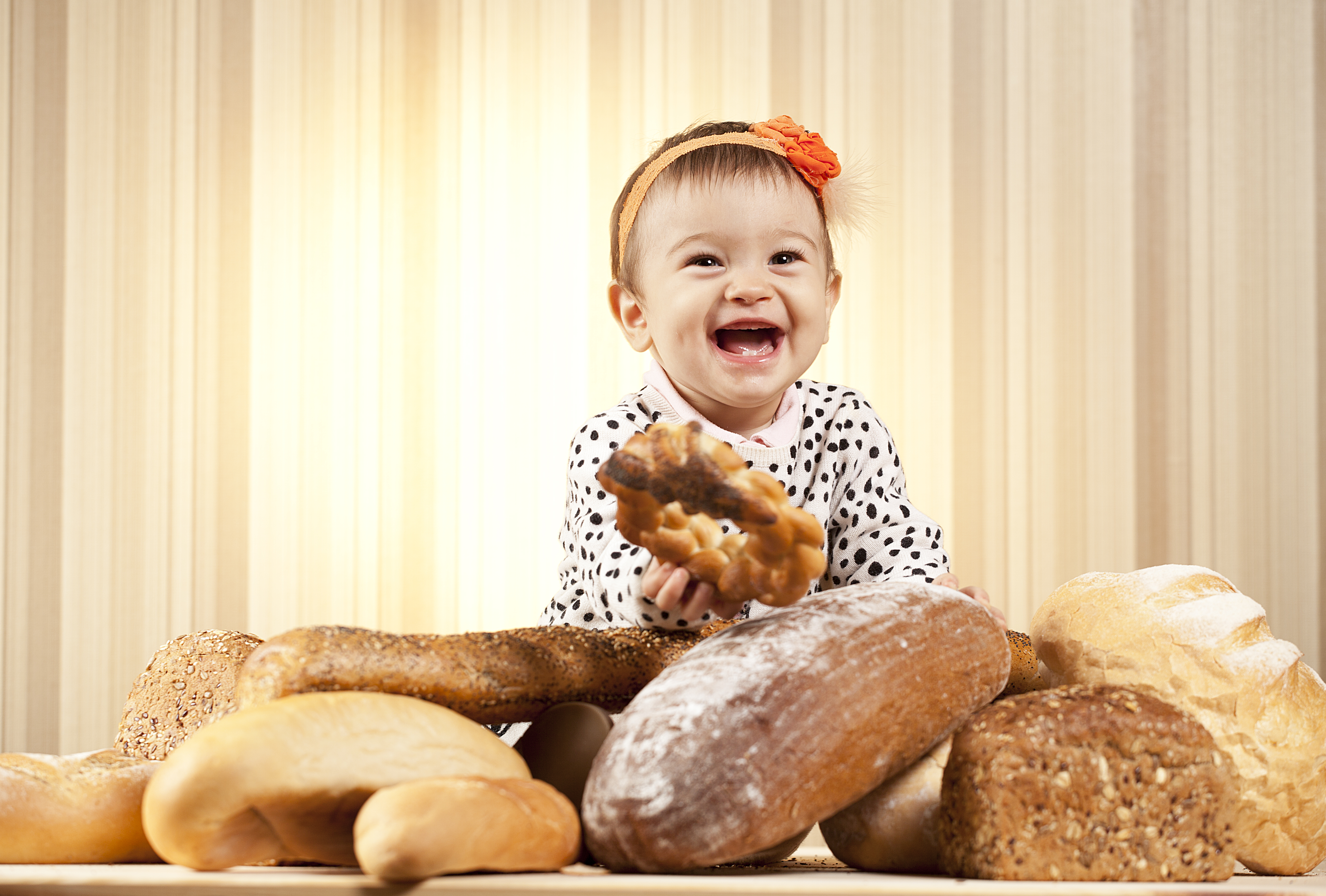 bebé sentado sonriendo rodeada de diferentes tipos de panes