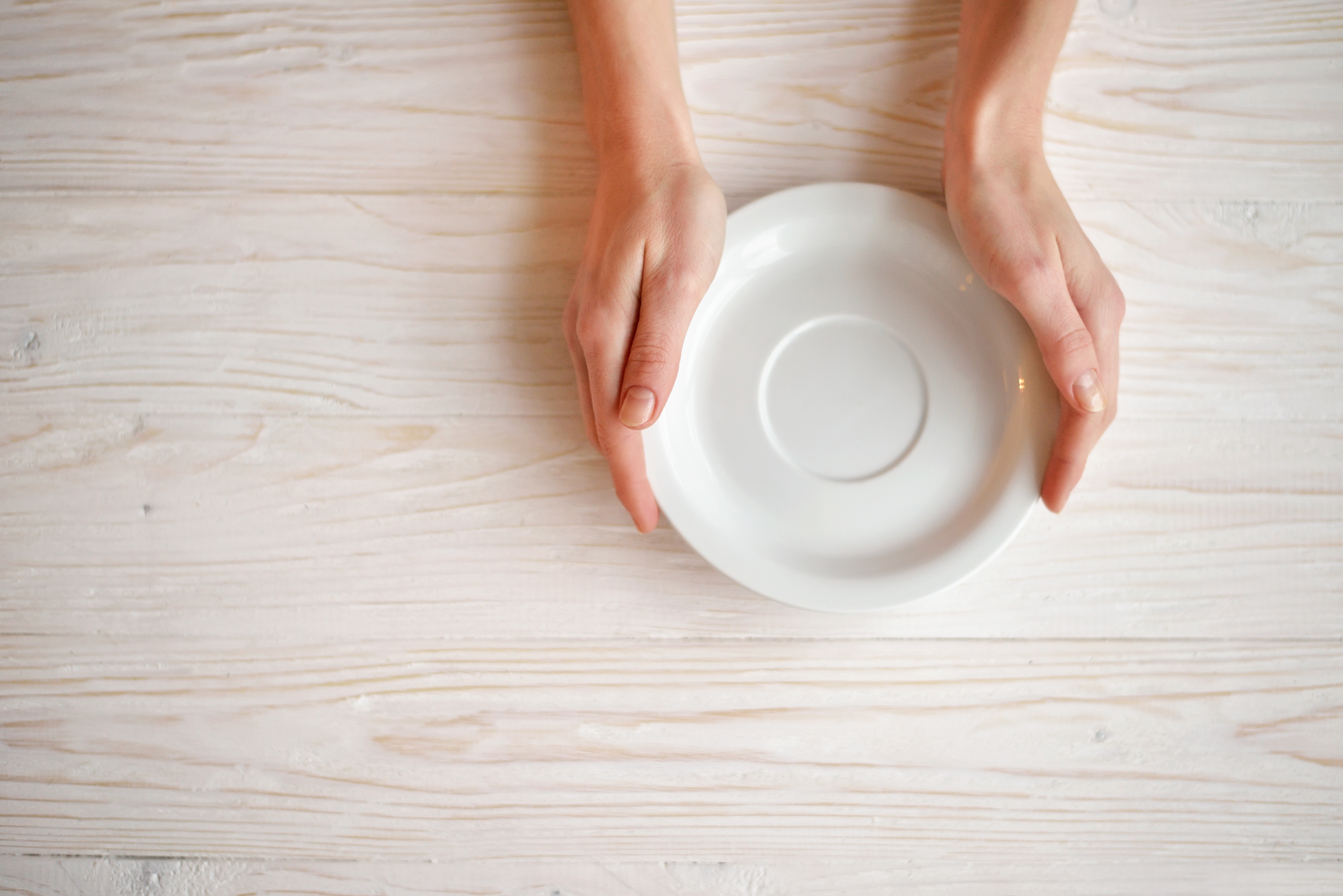 foto de dos manos rodeando un plato vacío sobre una mesa