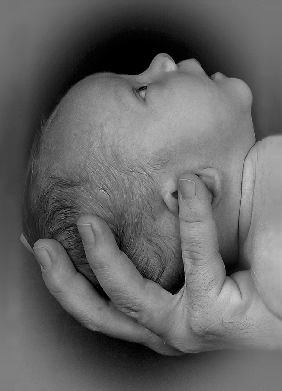 cabeza de bebé sostenida por mano