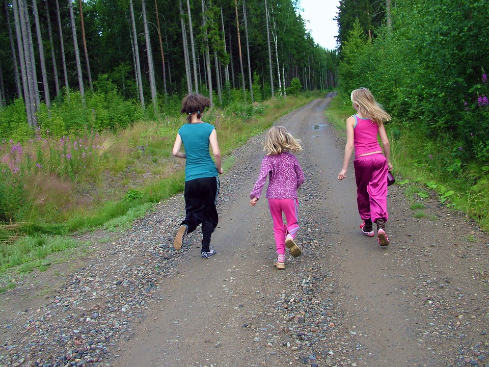 Mujer y niñas caminando ligero por el campo