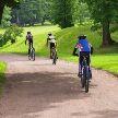 Tres ciclistas de mountain bike de espaldas circulando sobre un paisaje verde 