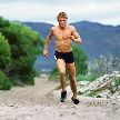 Hombre con el torso desnudo corriendo por la montaña
