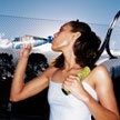 Mujer bebiendo agua y sujetando una raqueta de tenis