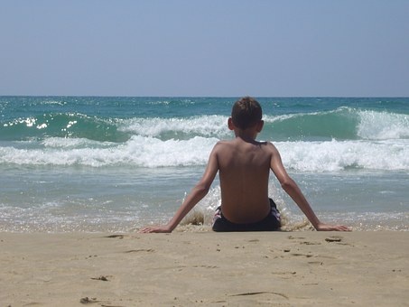 Niño sentado en la arena de la playa