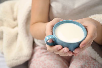 manos sujetando taza de leche