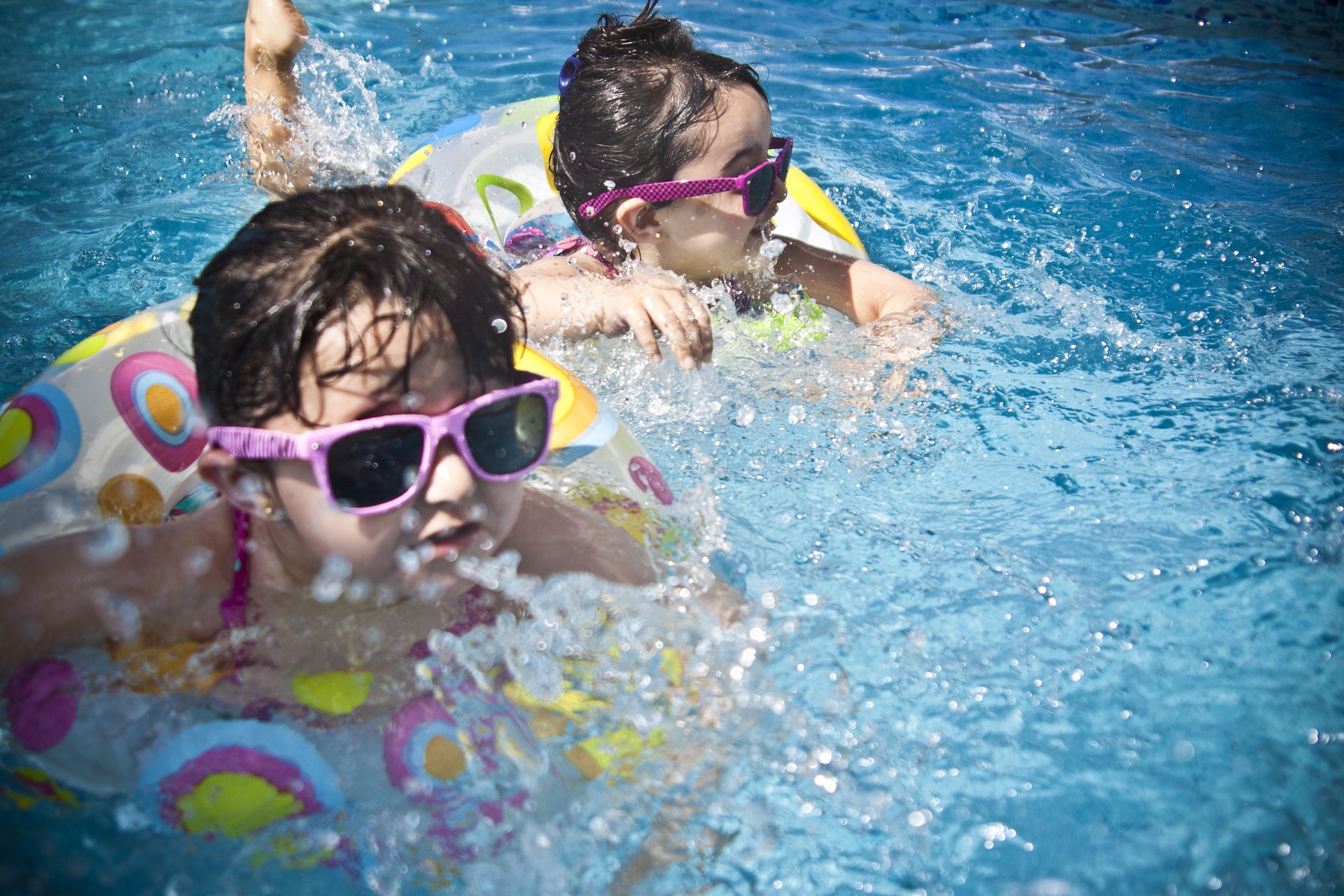 niñas pequeñas bañándose en la piscina con flotadores