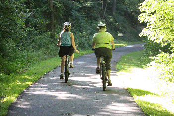 Dos adultos montando en bicicleta en zona arbolada