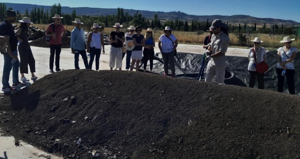 Grupo de personas frente a una hilera de compost