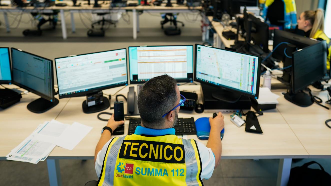 Técnico en Emergencias Sanitarias del SUMMA 112 sentado en su puesto de gestión de recursos en el centro coordinador del SUMMA 112 con sus tres pantallas al frente 