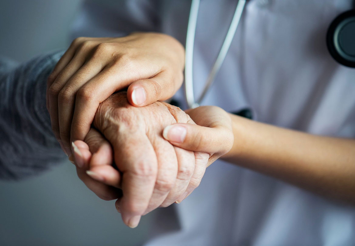 Hand of a doctor holds the hand of an elderly man
