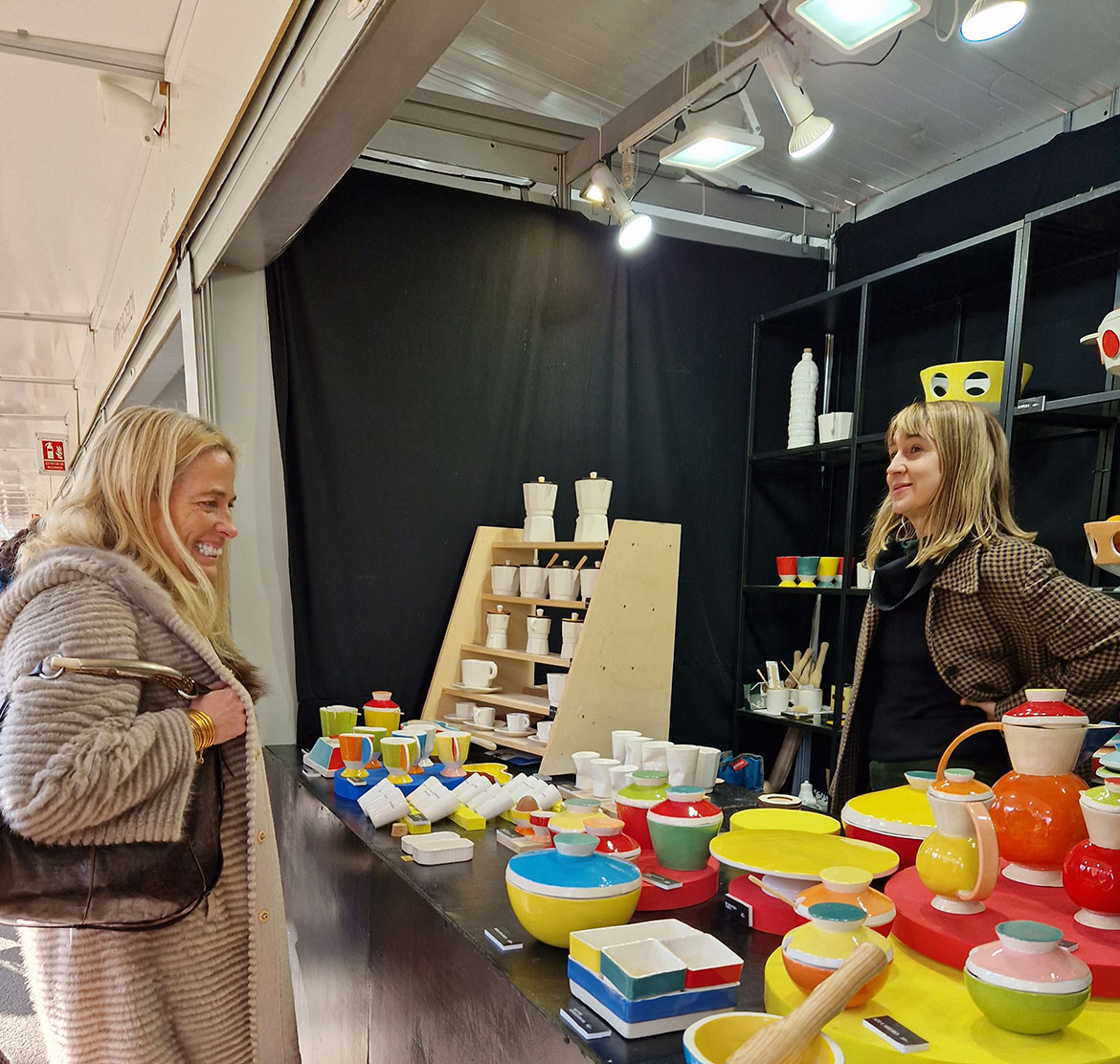 Woman in front of a craft stall attended by a saleswoman