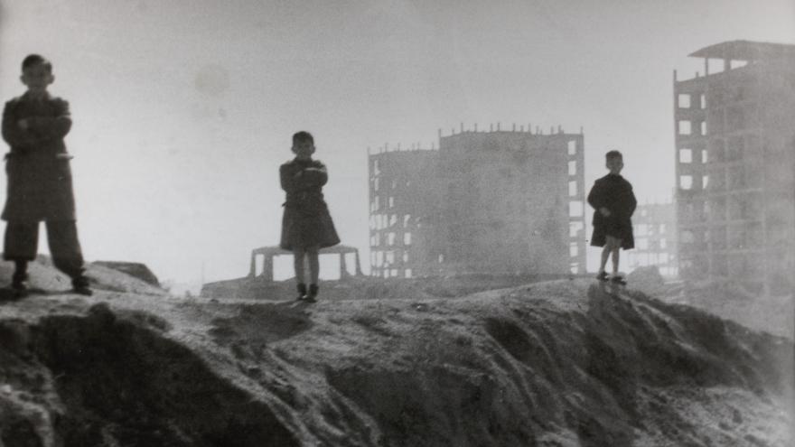 Three children pose for a photo in a ruined Madrid