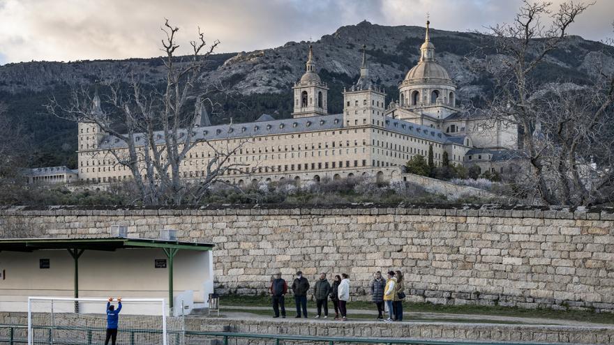 Espectadores en un campo de fútbol con edificio histórico detrás