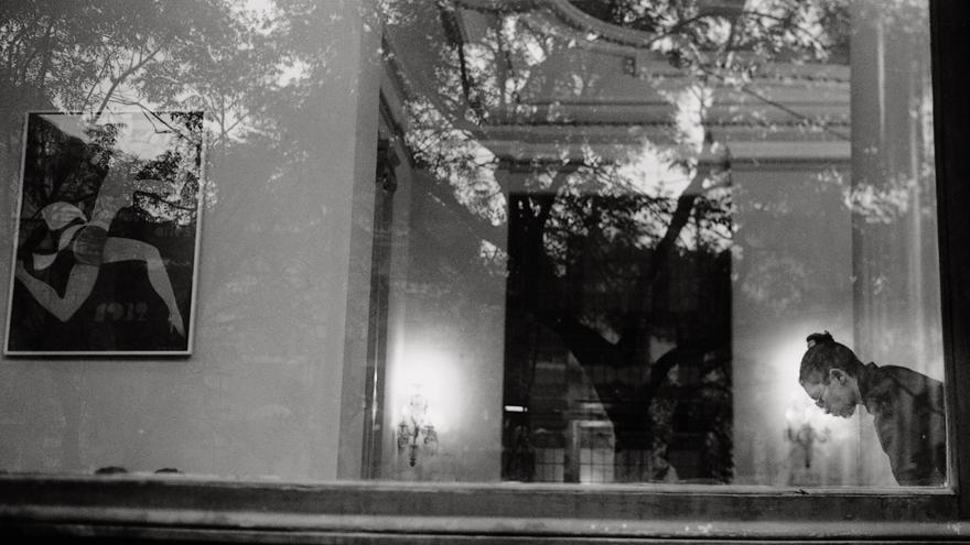 Una fotografía en blanco y negro donde se ve un cristal y una persona detrás