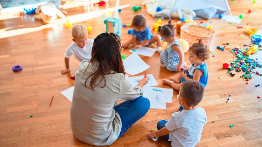 Niños sentados en el suelo con su maestra