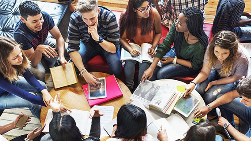 Jóvenes hablando alrededor de una mesa con libros