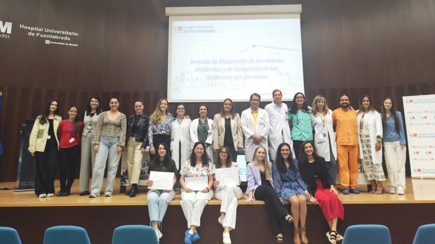 Jóvenes sentados y de pie con un diploma en un salón de actos 