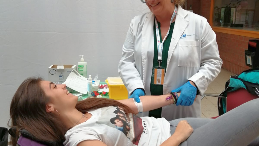 Una joven en la camilla mientras uan enfermera le extrae muestra de sangre para registro como donante de médula