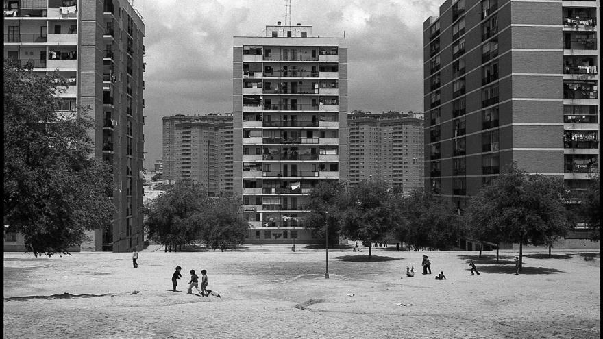 solar donde juegan los niños con edificios al fondo del barrio de El Pilar en los años 70