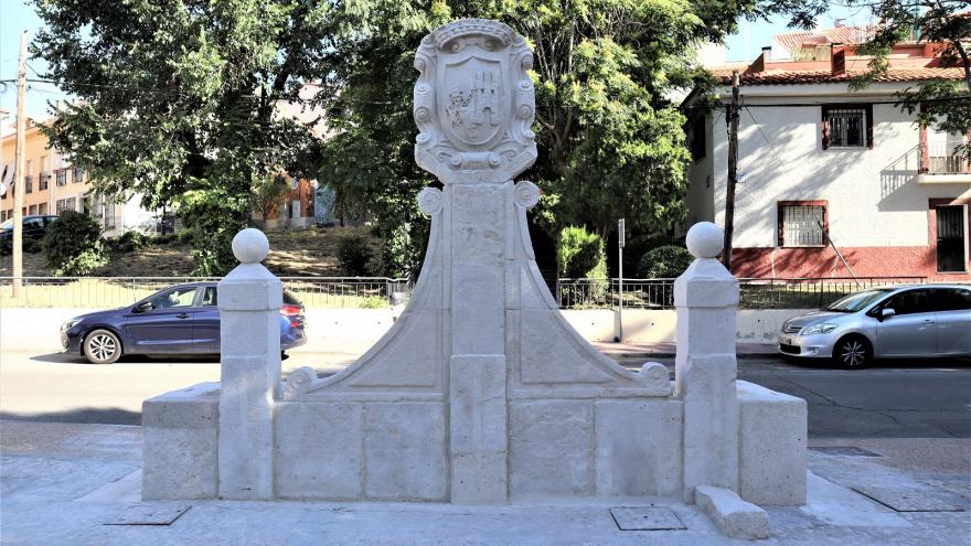 Image of the stone fountain with a central shield, two small columns and a water basin