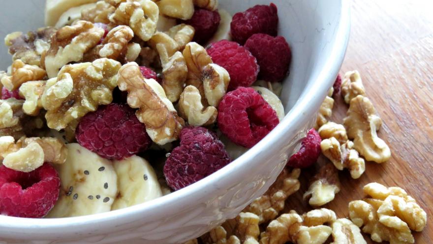 Cuenco con nueces frambuesas y un platano 