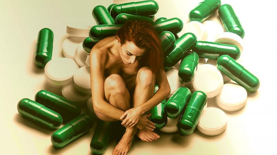 Mujer sentada sobre pastillas y medicinas