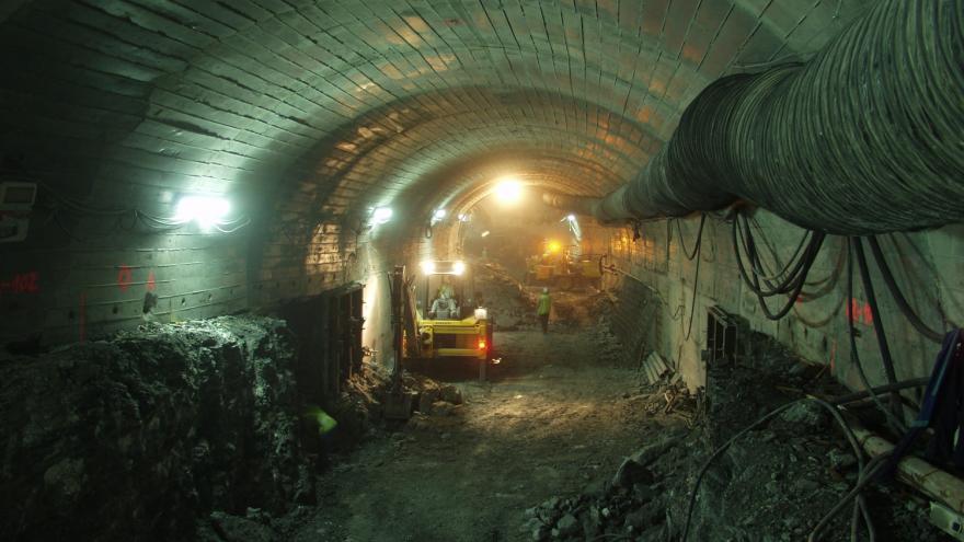 Túnel iluminado en obras con maquinaria y obreros trabajando