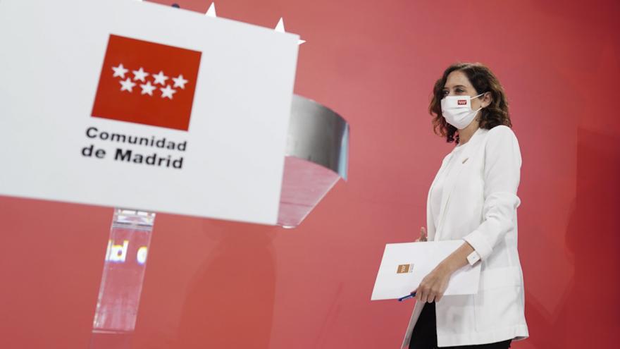 La presidenta caminando al atril con el logotipo de la Comunidad de Madrid
