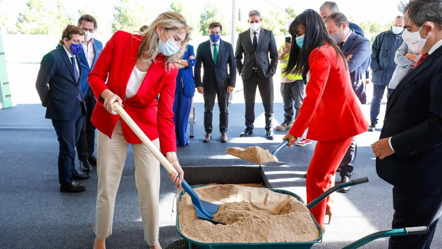 La consejera con una pala cogiendo arena de una carretilla como símbolo de la colocación de esa primera piedra