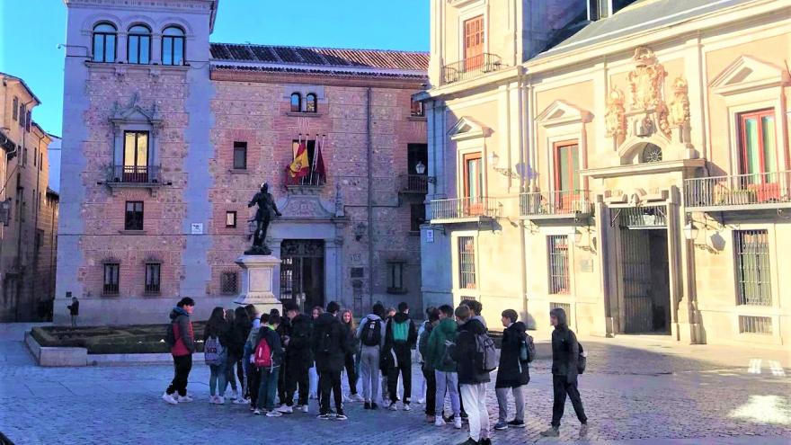 Grupo de jóvenes en una plaza de Madrid y al fondo edificios