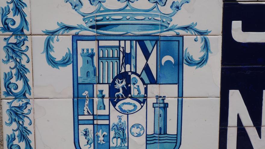 escudo de azulejos en azul sobre fondo blanco, cuartelado coronado con los símbolos de la antigua diputación de Madrid