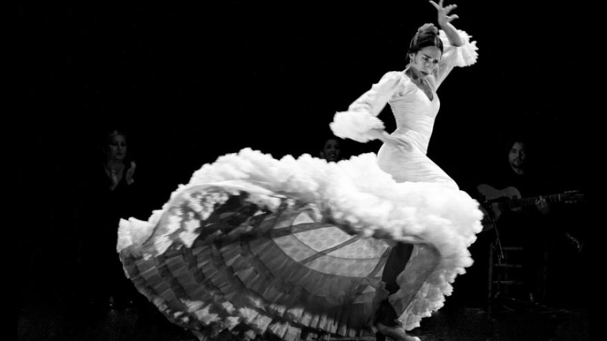 imagen de una mujer bailando flamenco con una bata de cola blanca