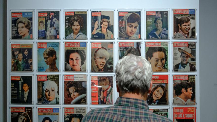 Man looking at magazine cover posted on a wall