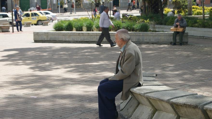 hombre mayor sentado en un banco de la calle