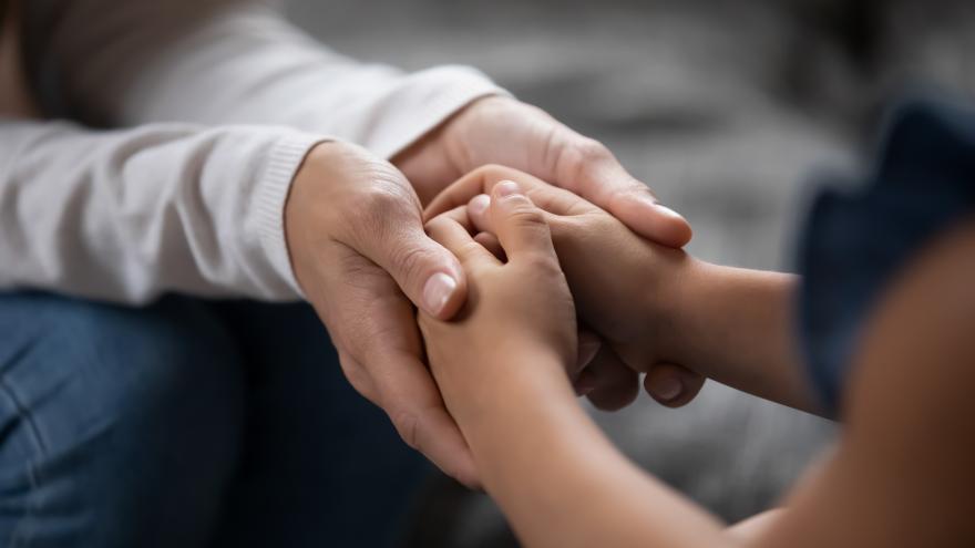 Una mujer le da las manos a un niño